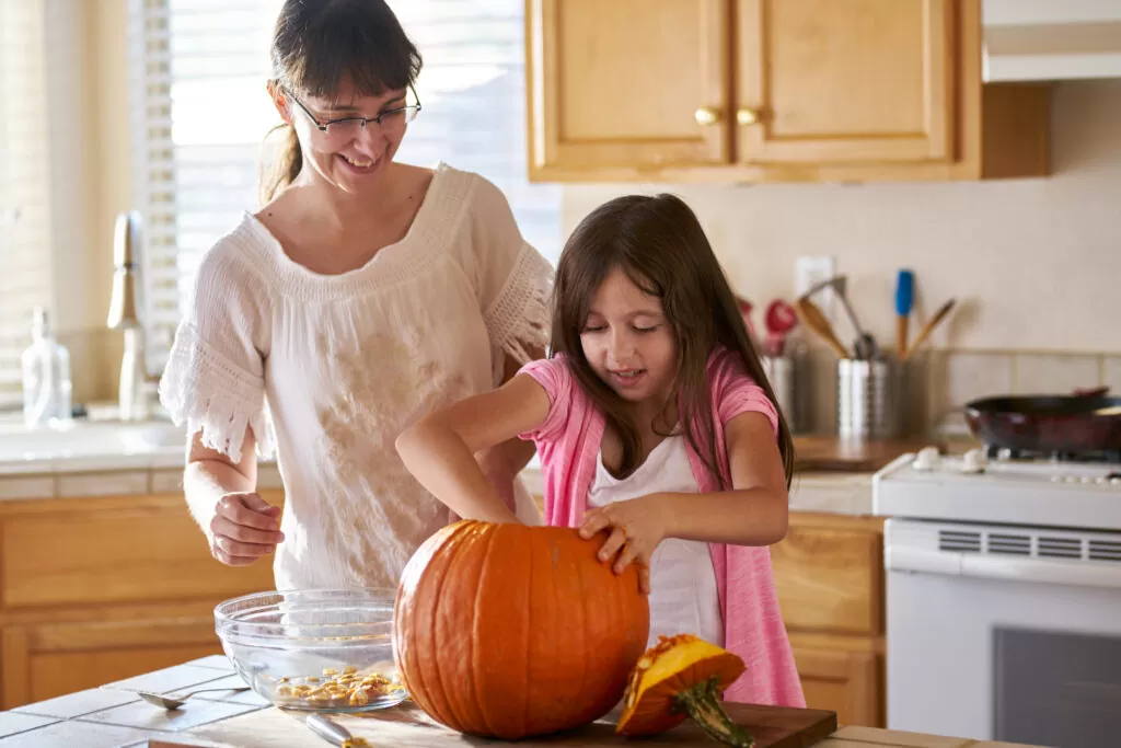 mother and daughter cleaning insides of a pumpkin