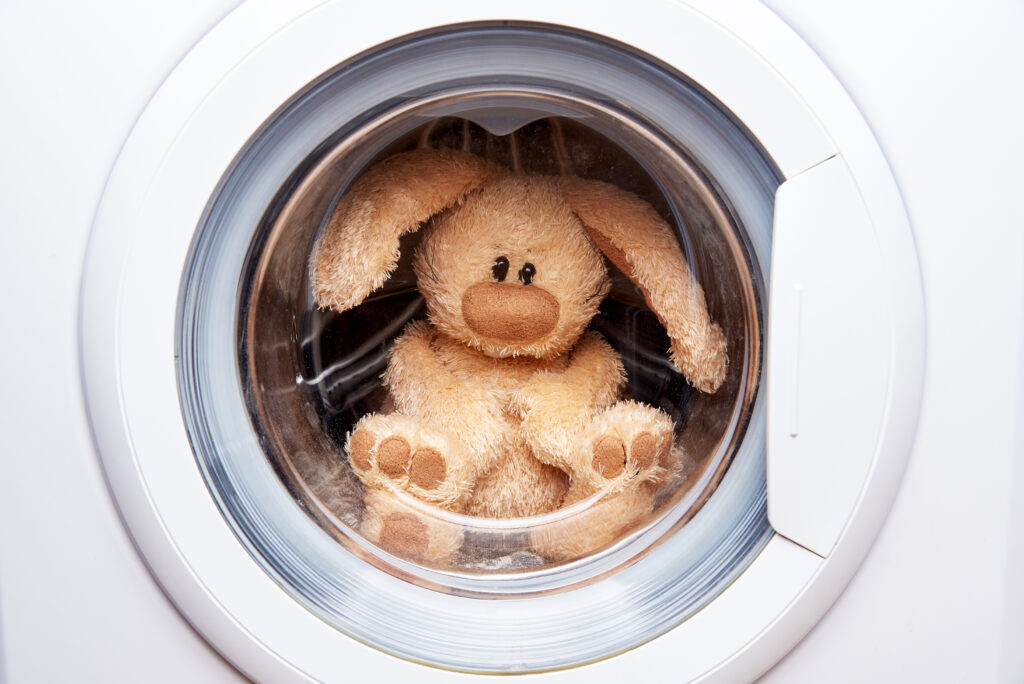 Stuffed rabbit toy in a closed washing machine.