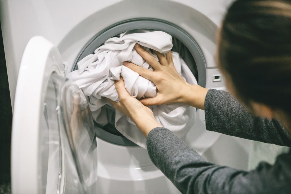 the-girl-puts-the-laundry-in-the-washing-machine-2021-10-28-22-22-55-utc