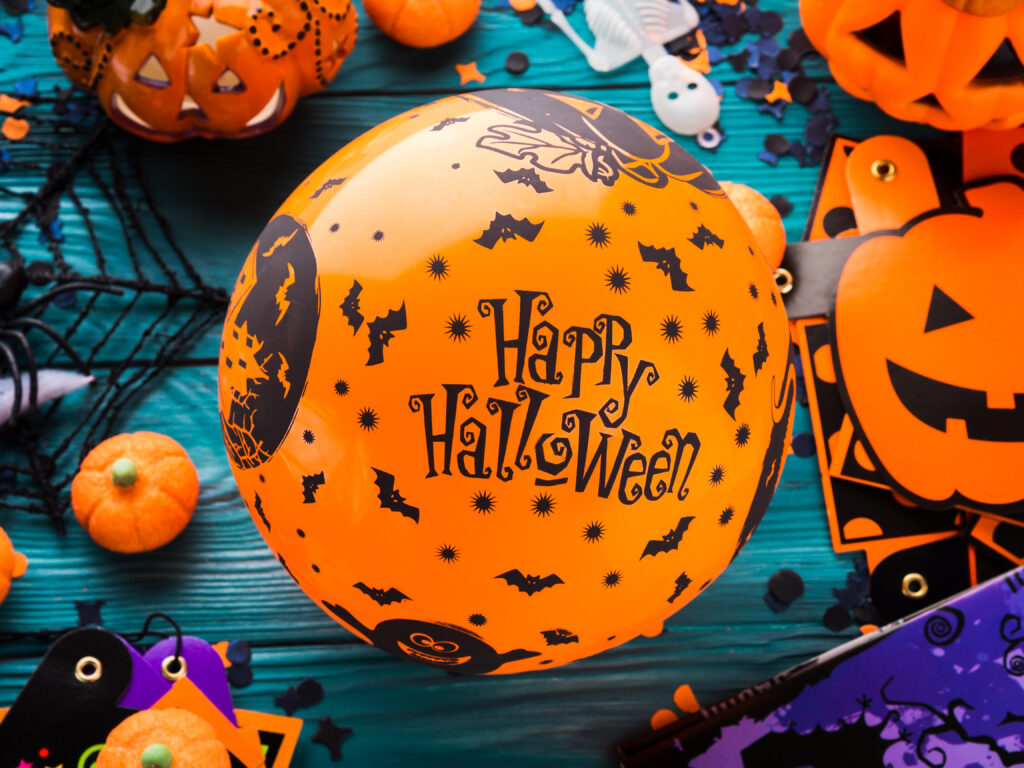 Halloween decoration symbols on dark rustic wooden background. Wishing happy holiday with orange balloon
